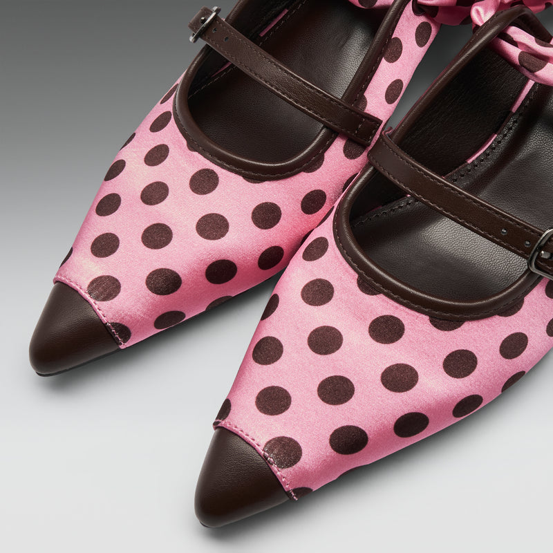 Pink satin Mary Jane shoes with dark brown polka dots, dark brown leather pointed toes, and matching dark brown straps, shown on a neutral gray background.