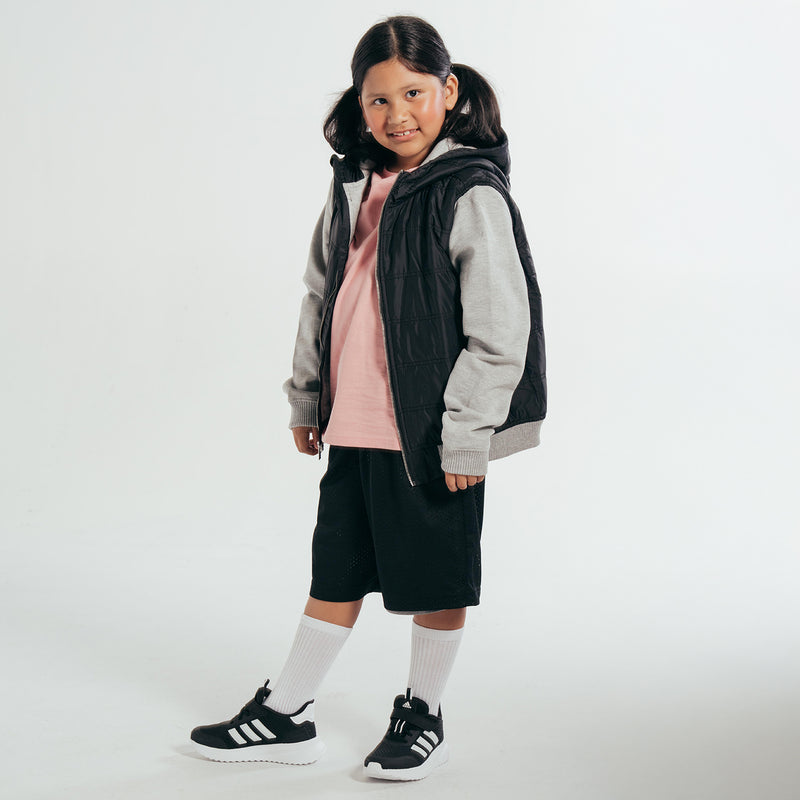Youth puffer jacket worn by child, black quilted vest style with gray sleeves