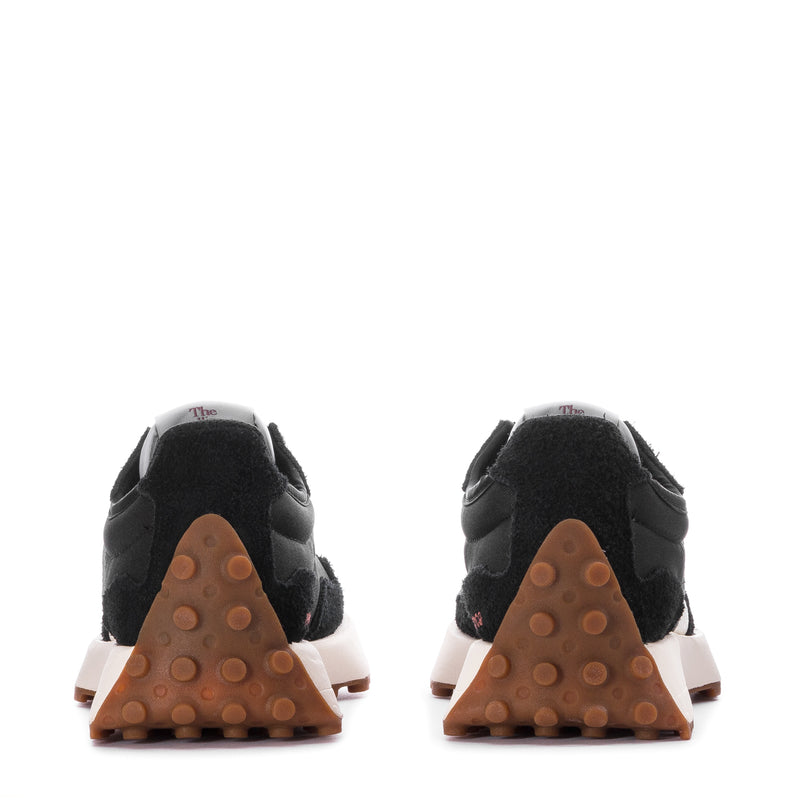 Women's black sneakers with white midsole trim and gum rubber heel tread.