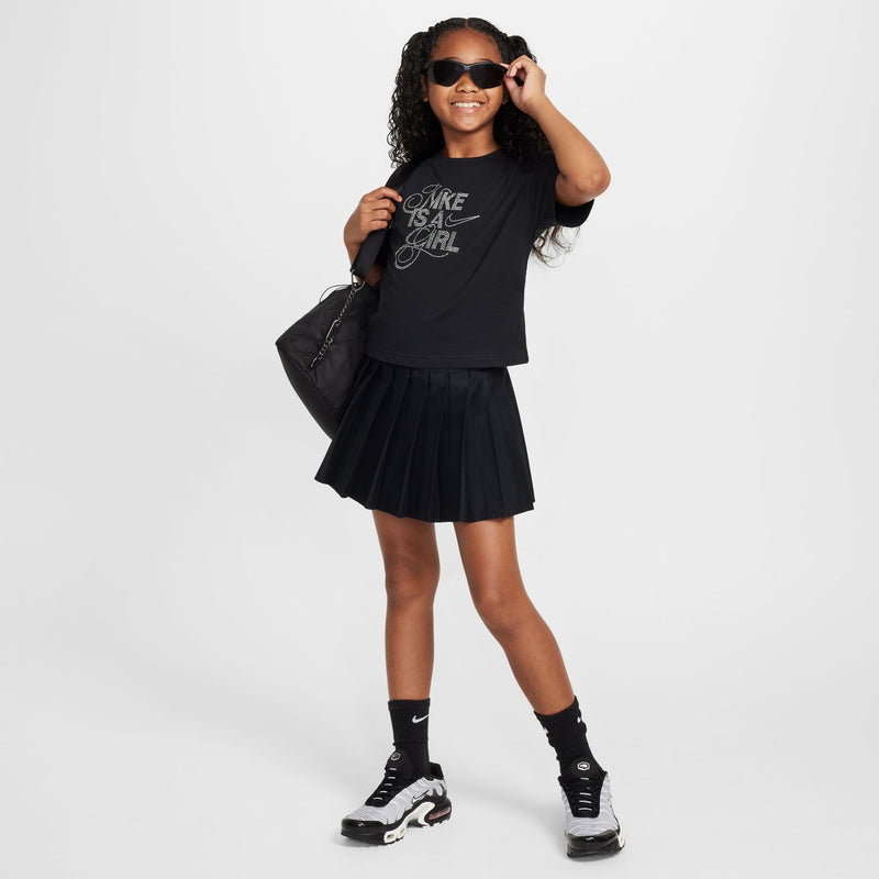 Youth black tee worn with pleated skirt, 'Nike is a girl' graphic