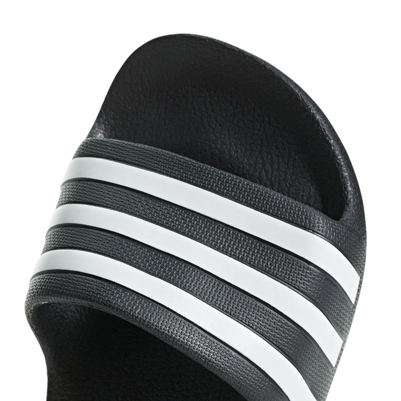 Kids black slide sandal upper close-up with white triple stripes
