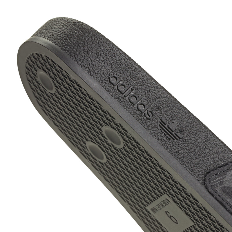 Men's black slide sandals close-up of insole branding and leaf-patterned footbed texture