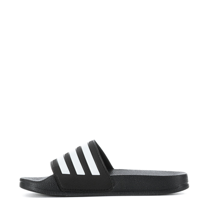 Kids black slide sandals with white adidas stripes, side angle view