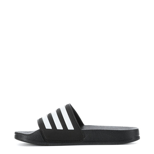 Kids black slide sandals with white adidas stripes, side angle view