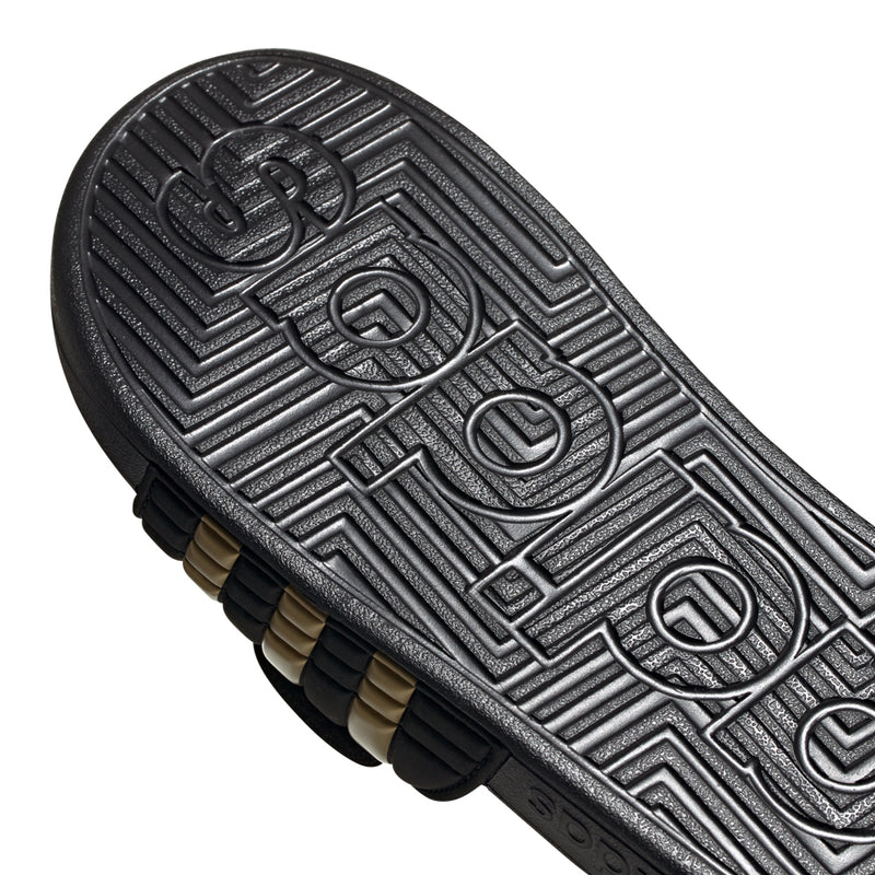 Men's black slide sandal outsole tread with adidas lettering and gold underlayer