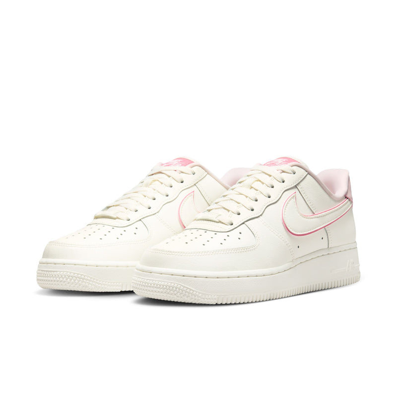 Pair of womens low-top Nike Air Force 1 sneakers, sail white with pink accents
