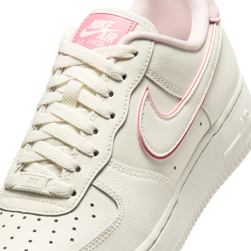Close-up of womens Nike Air Force 1 upper with sail leather, pink swoosh, and lace eyelets