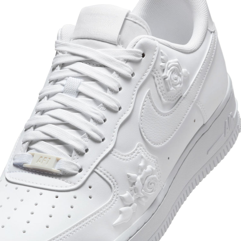Women's Nike white sneaker close-up of laces, tongue, and embossed floral Swoosh
