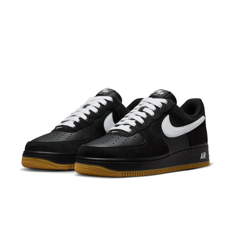 Pair of black low-top sneakers with white swooshes and gum rubber outsole.
