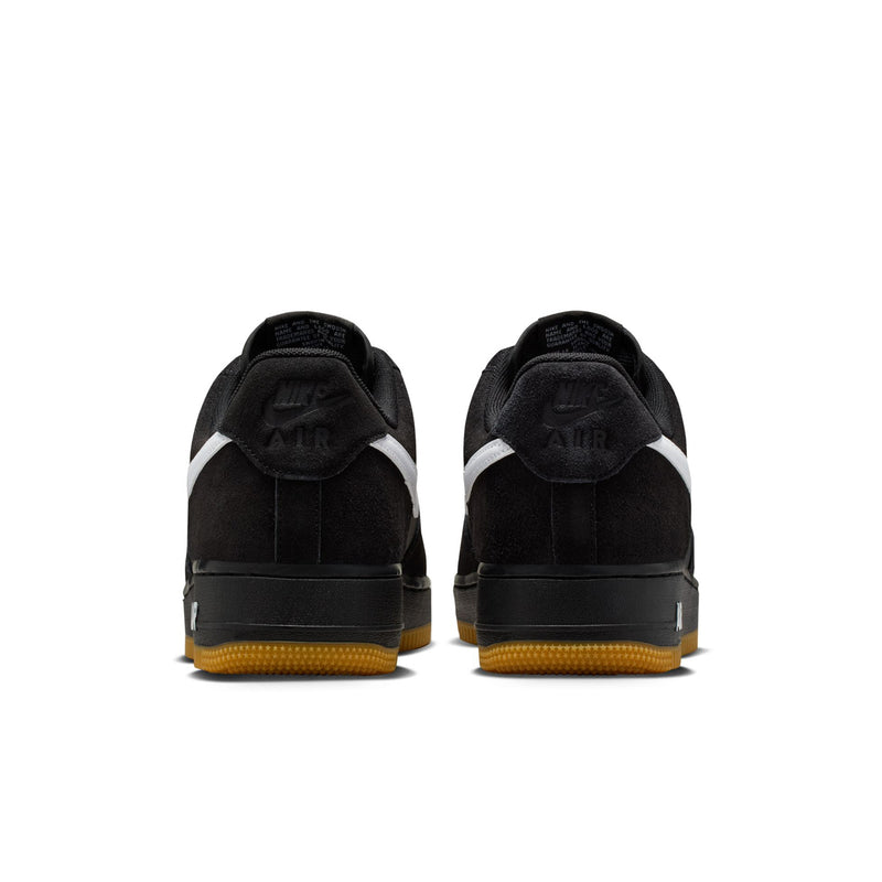 Black low-top sneakers with white heel stripe and gum outsole, rear view.