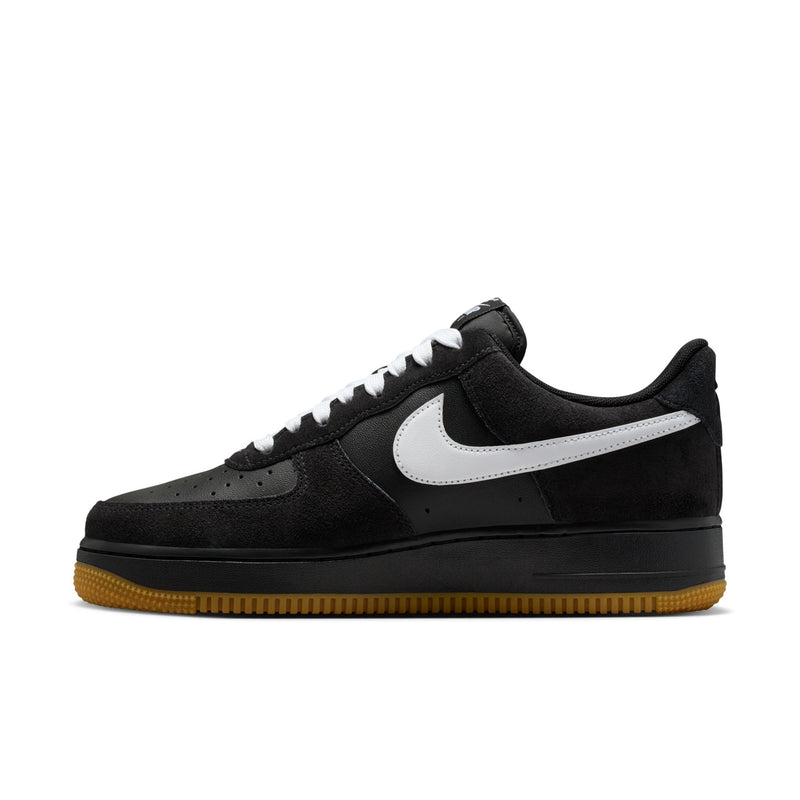 Black low-top sneakers with white swoosh, lace eyelets, and gum outsole.