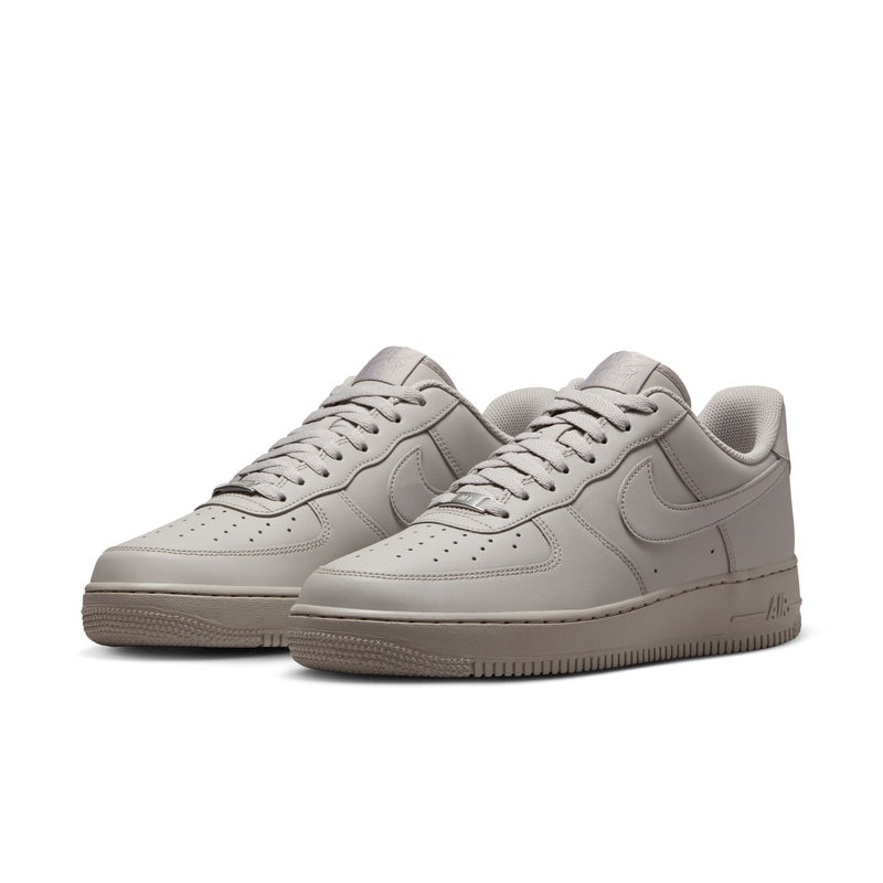 Pair of light gray Nike low-top lace-up sneakers with perforated toe and swoosh