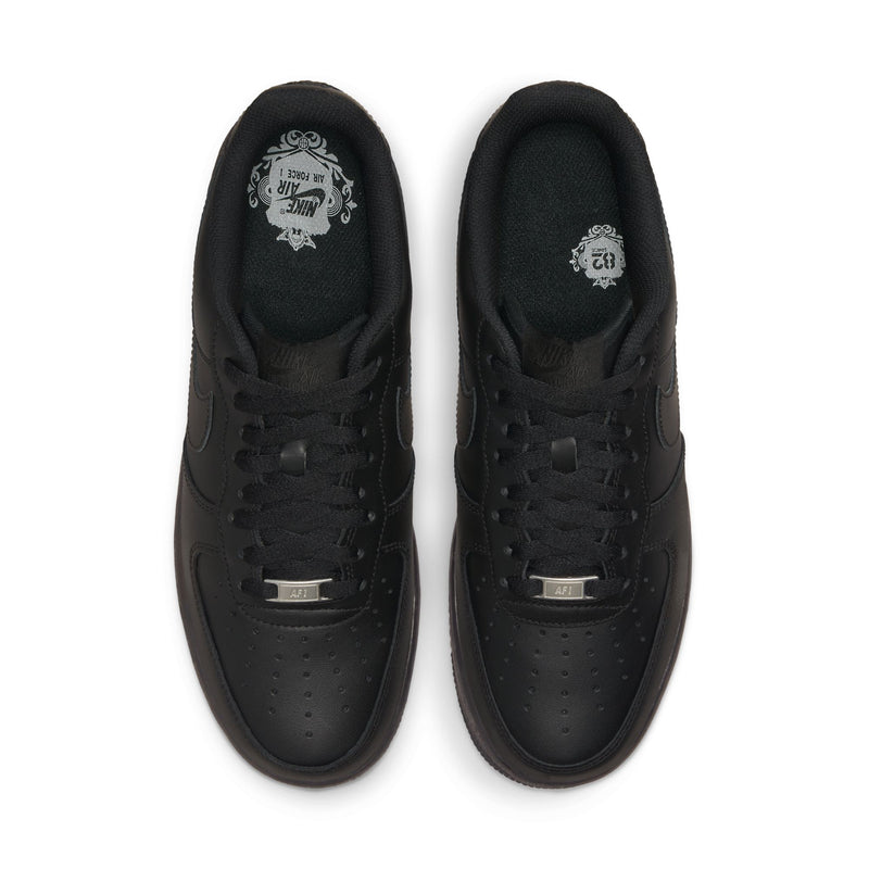 Pair of black low-top sneakers showing laces, perforations, and metal lace tag