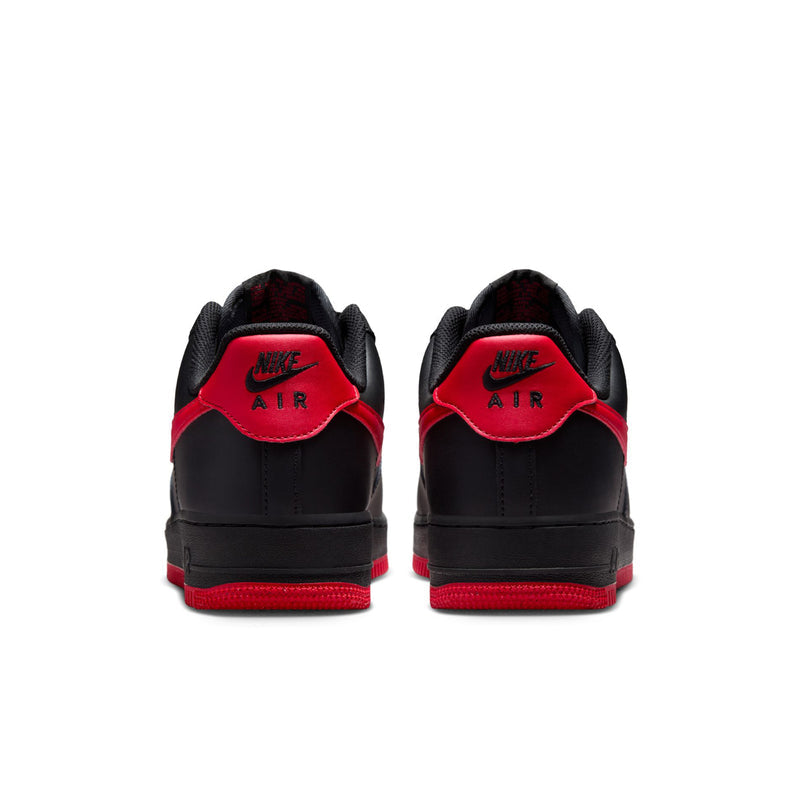Black low-top Nike sneakers with red heel tabs and red outsole trim