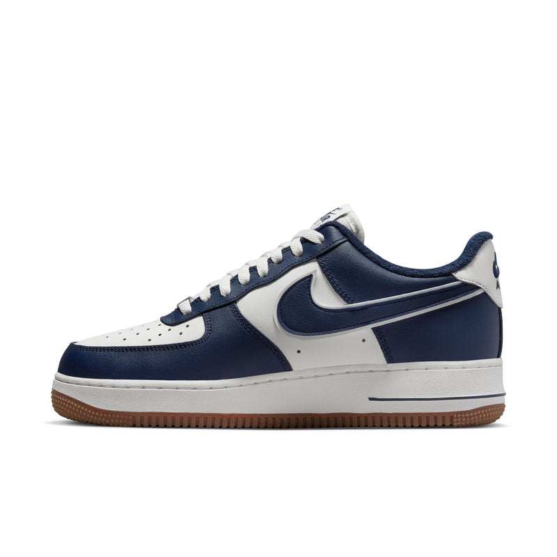 Side profile of navy and white low-top sneakers with swoosh logo and gum sole