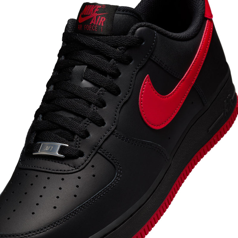 Black Nike low-top sneaker close-up with red swoosh and lace detail