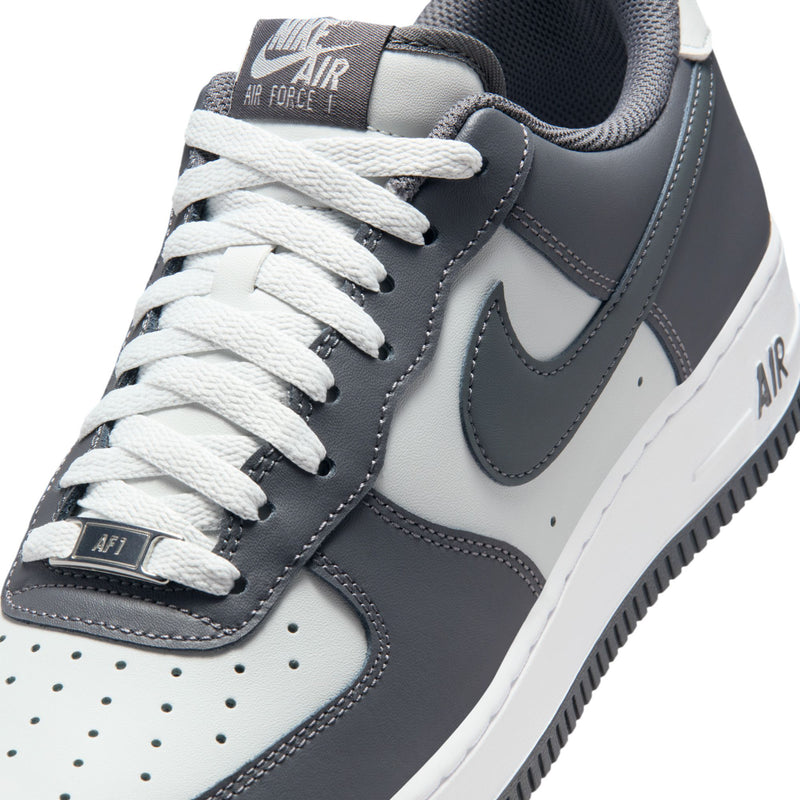 Men's sneaker close-up with white laces, dark eyelets, and padded collar