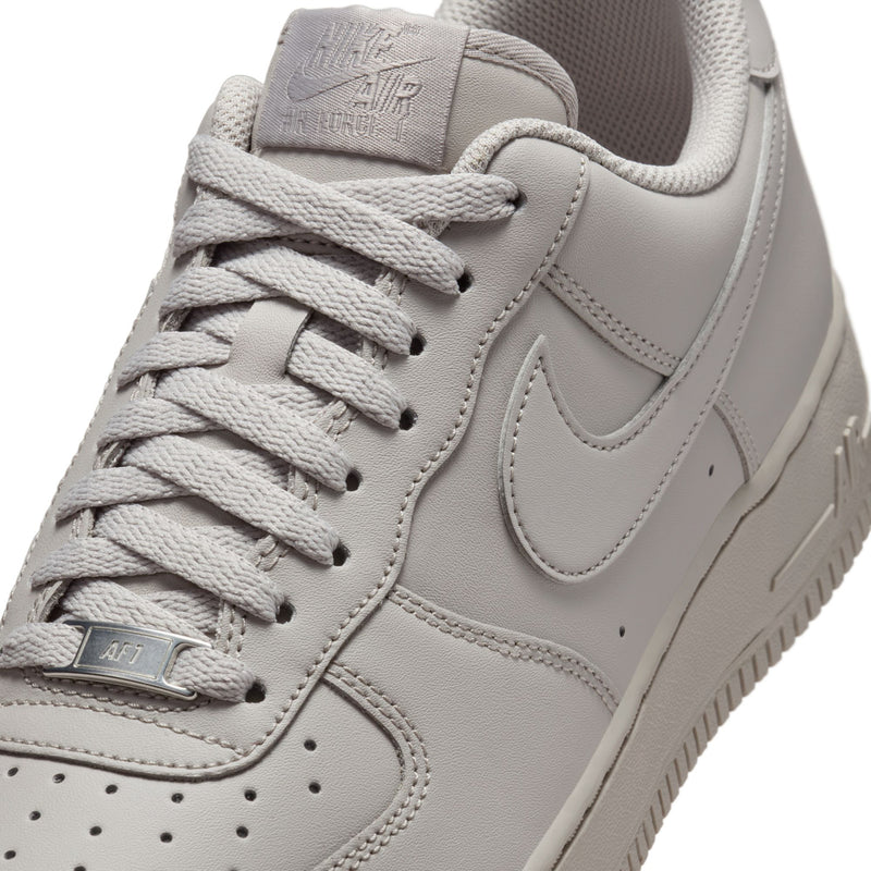 Light gray Nike low-top sneaker close-up of laces, swoosh, and perforated panels