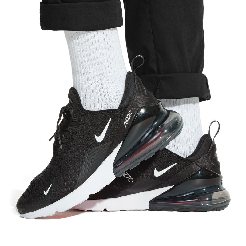 Air Max 270 sneakers on feet, black/white with visible air unit and red accents