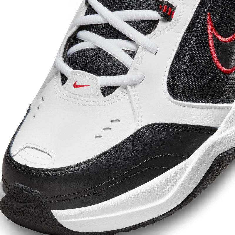 Close-up of men’s sneaker upper: white laces, black panels, red swoosh logo