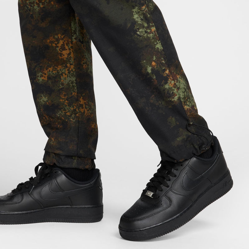 Men's woven camo pants with ankle cinch detail, worn with black sneakers