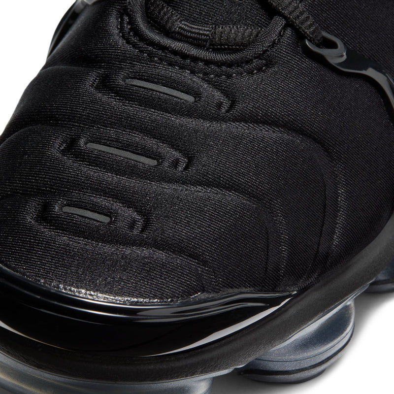 Black sneaker upper close-up with textured paneling and molded cushioning detail.