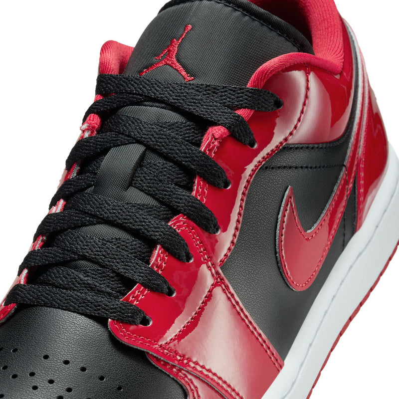 Close-up of men's low-top sneakers: black laces, black swoosh, red patent leather panels.