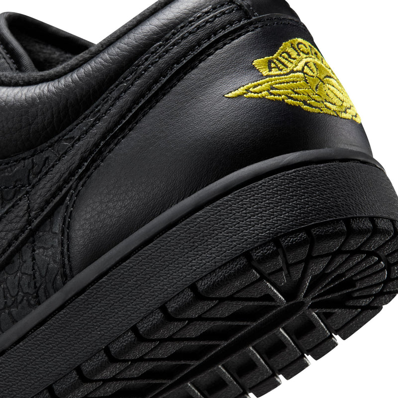 Close-up of black sneaker side with yellow Air Jordan wing logo and tread sole