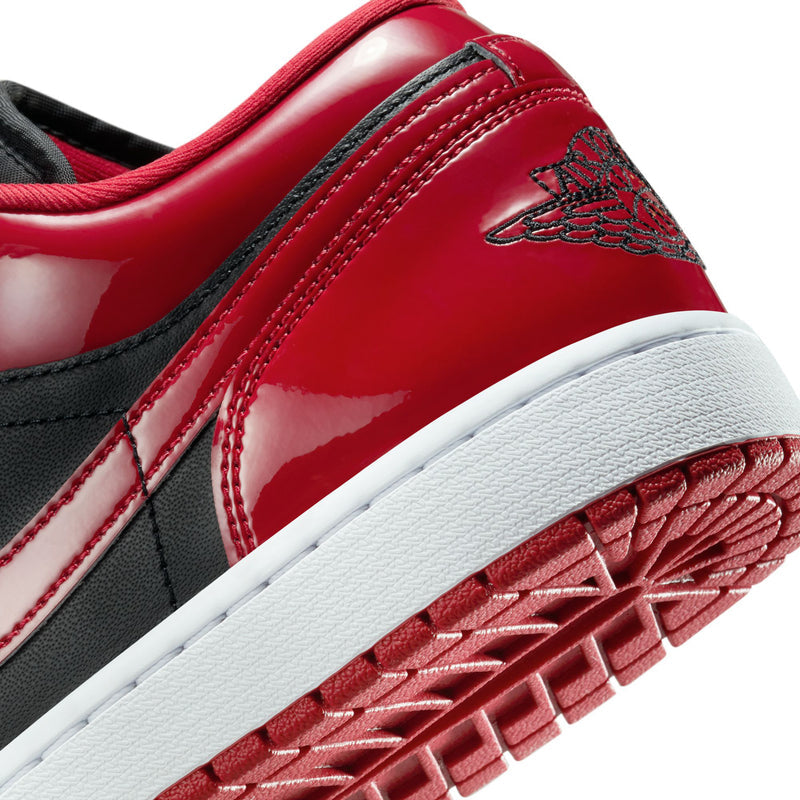 Close-up of men's low-top sneaker side with red patent finish and stitched detail.
