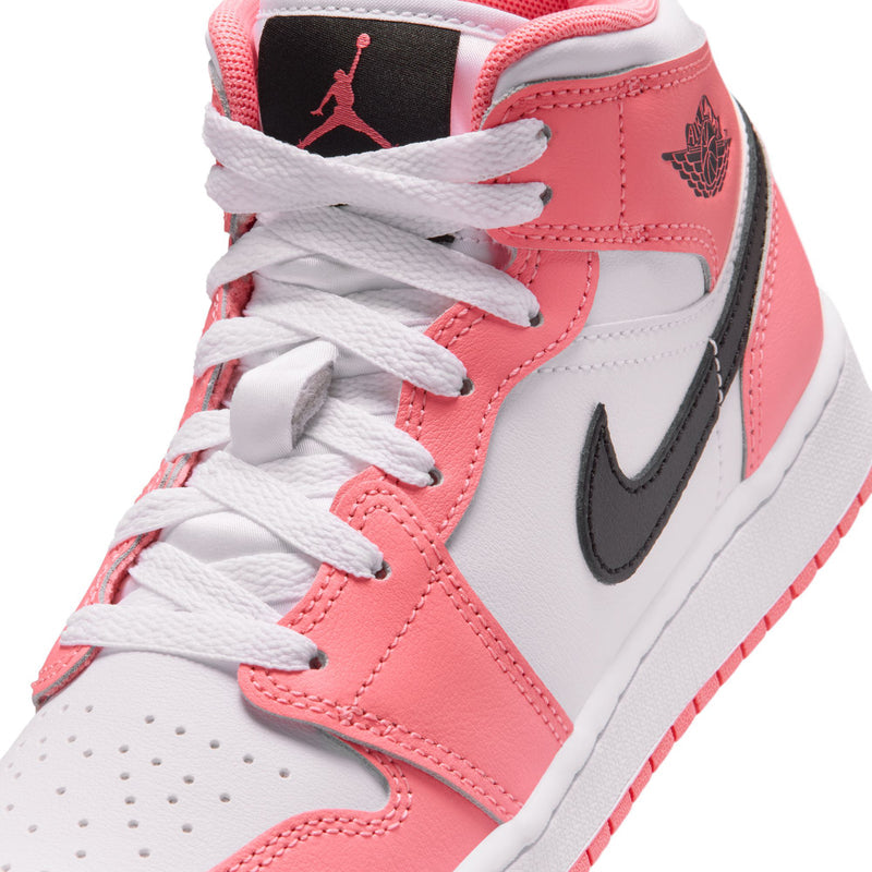 Youth mid-top sneaker close-up: pink and white upper with white laces and black swoosh