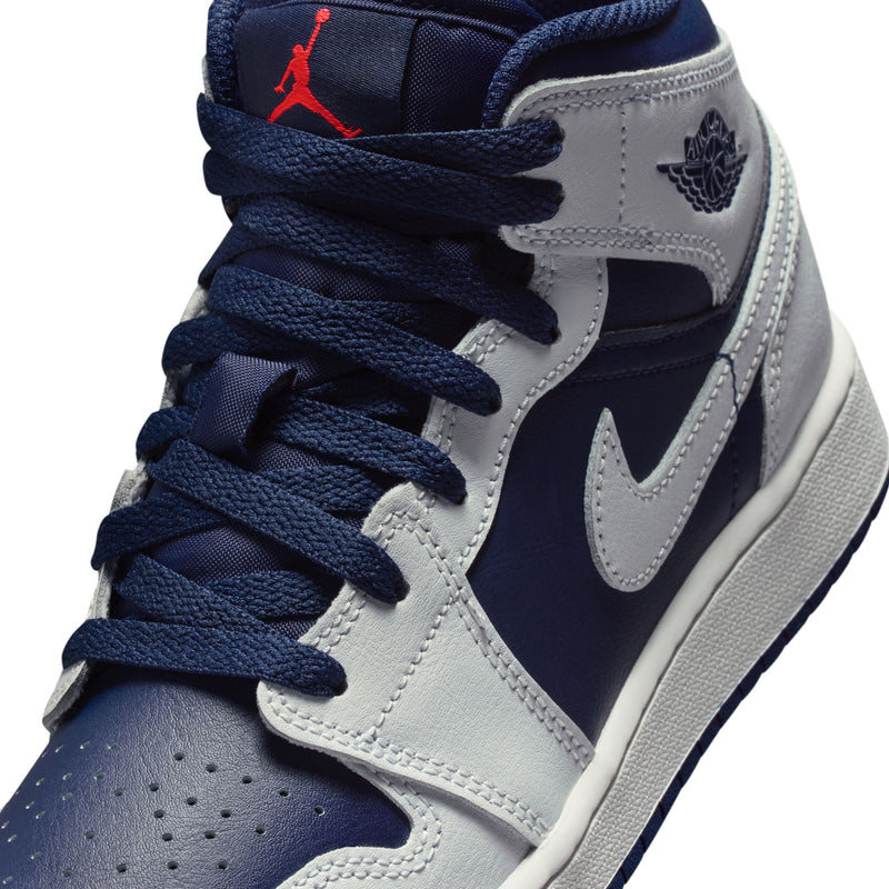 Youth mid-top sneaker close-up with navy laces, Wings logo, and red Jumpman