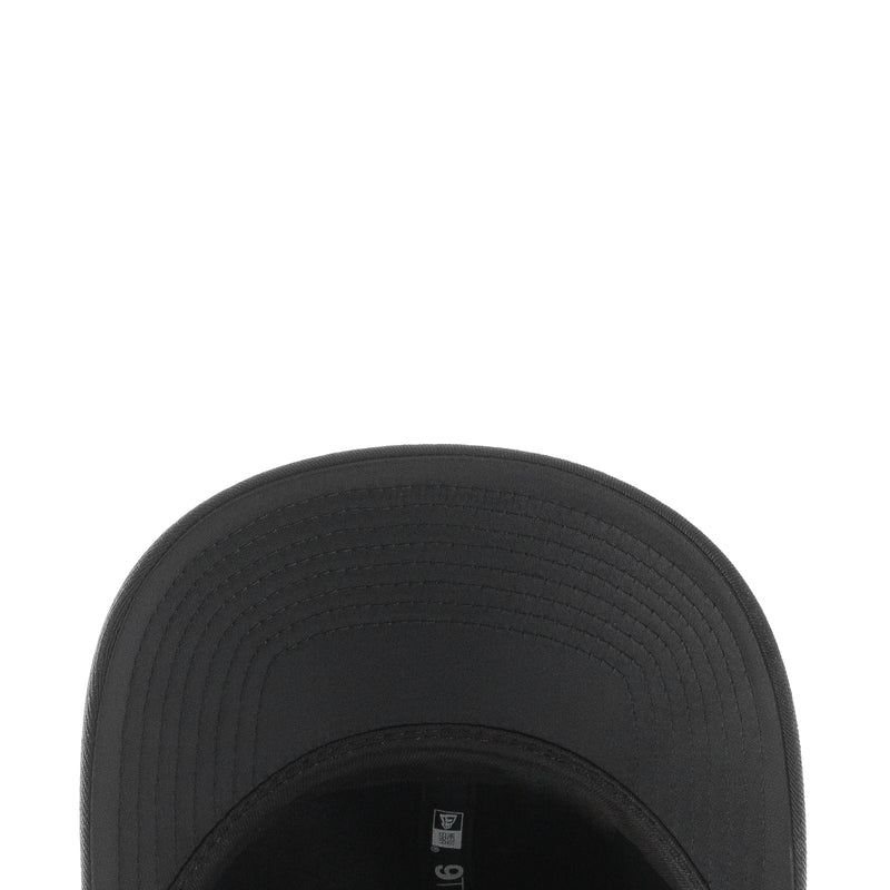 Black baseball cap brim close-up with stitched texture and curved edge