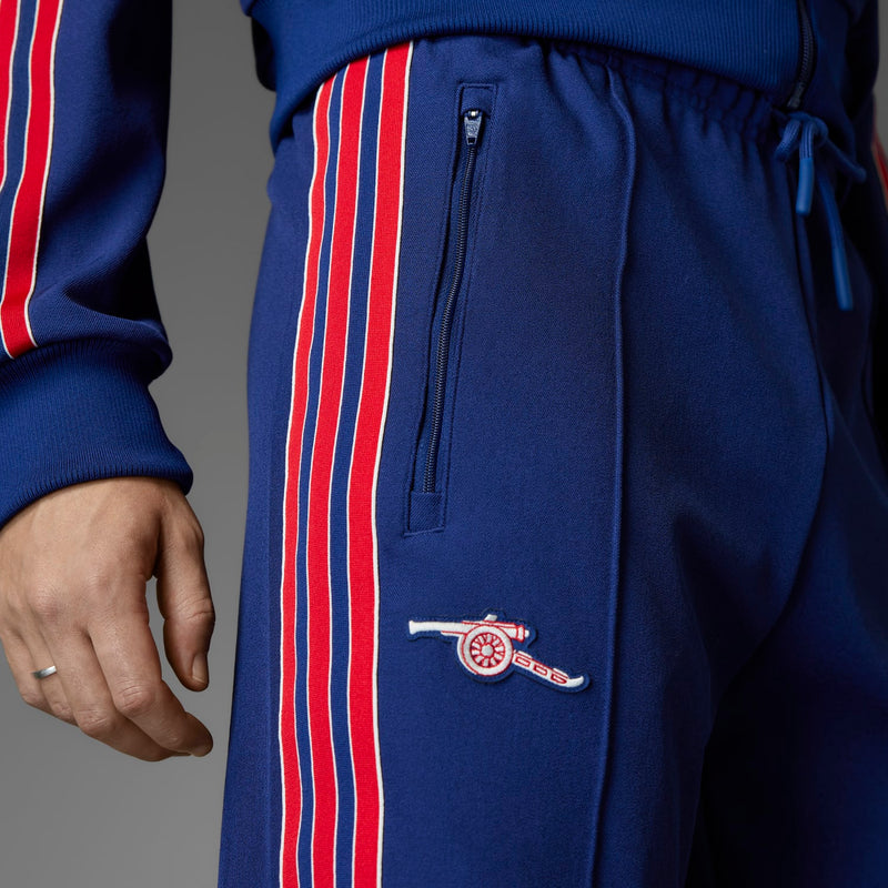 Blue track pants with zip pocket and embroidered crest on left thigh