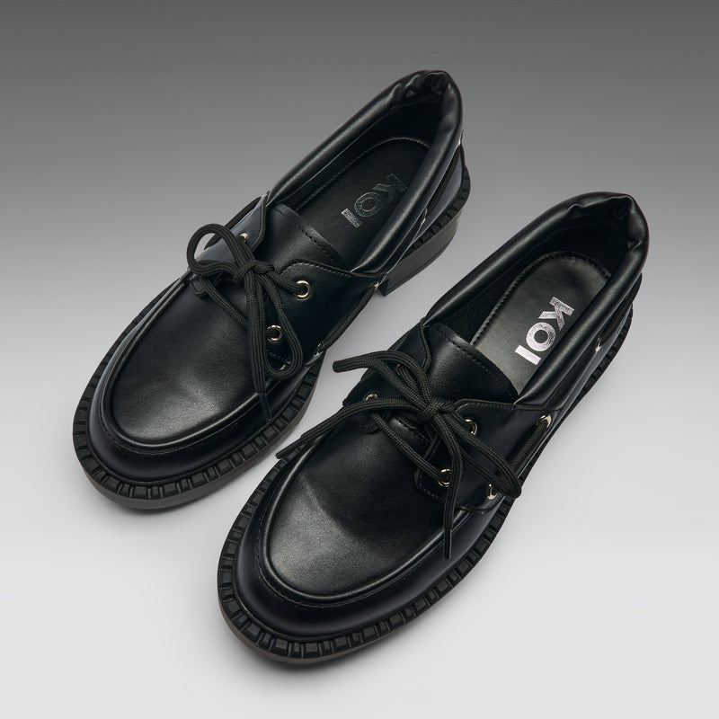 Pair of black leather shoes with brand logo on a gradient background