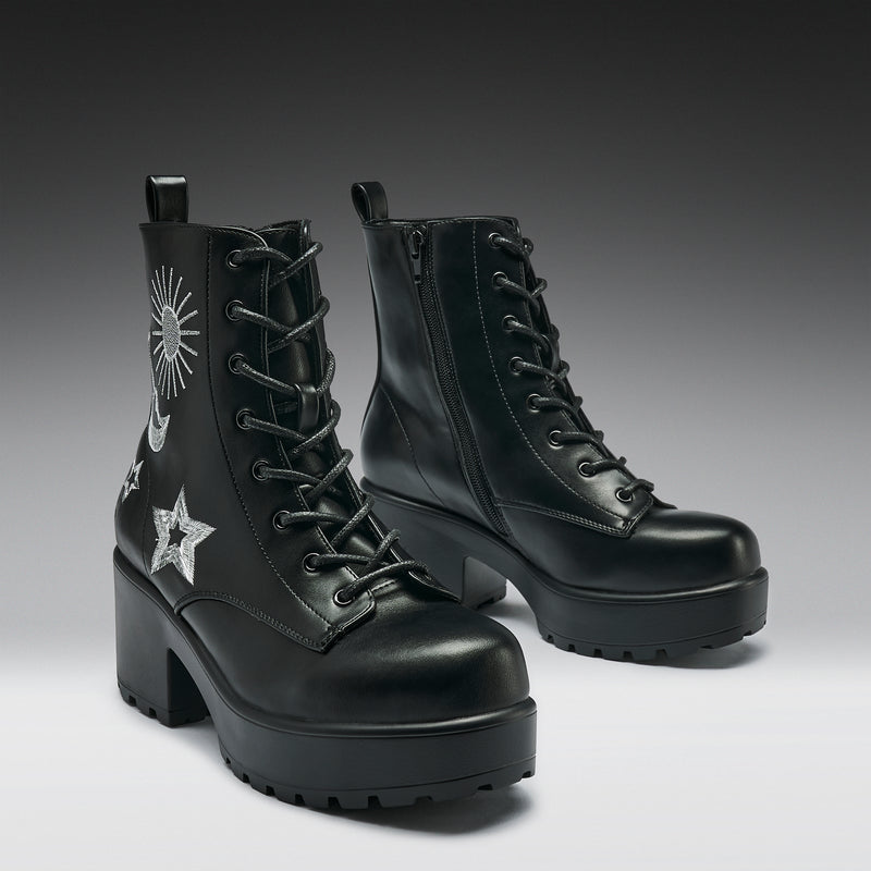 Black platform boots with star and moon designs on a gray background