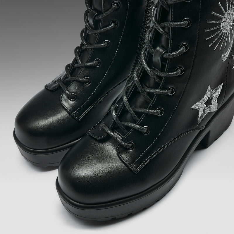 Black leather boots with star embroidery on a light gray background