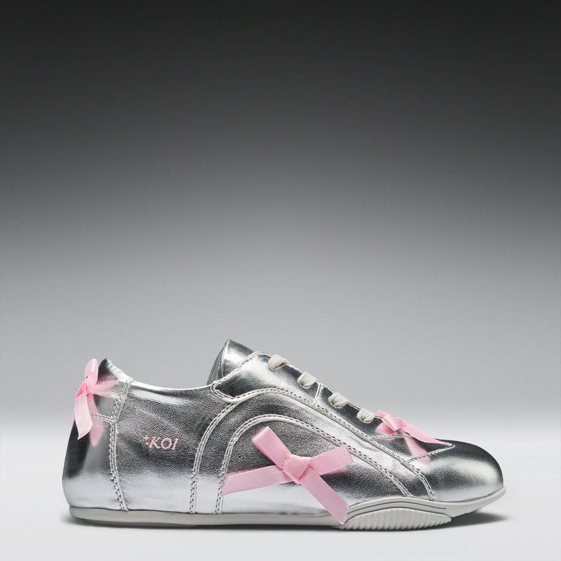 Silver sneaker with pink bows on a gray background
