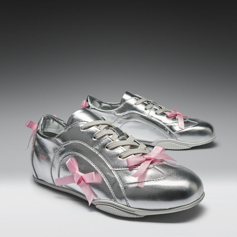 Silver sneakers with pink bows on a gray background