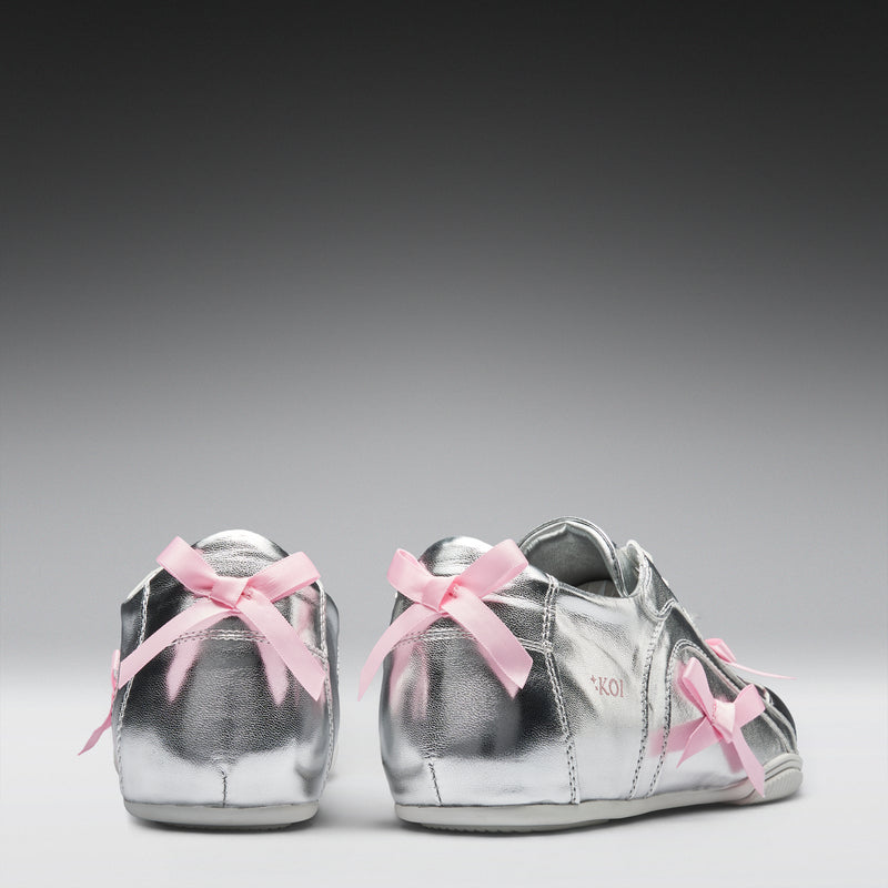 Silver sneakers with pink laces on a gray background