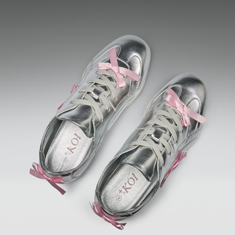 Silver sneakers with pink laces on a light gray background
