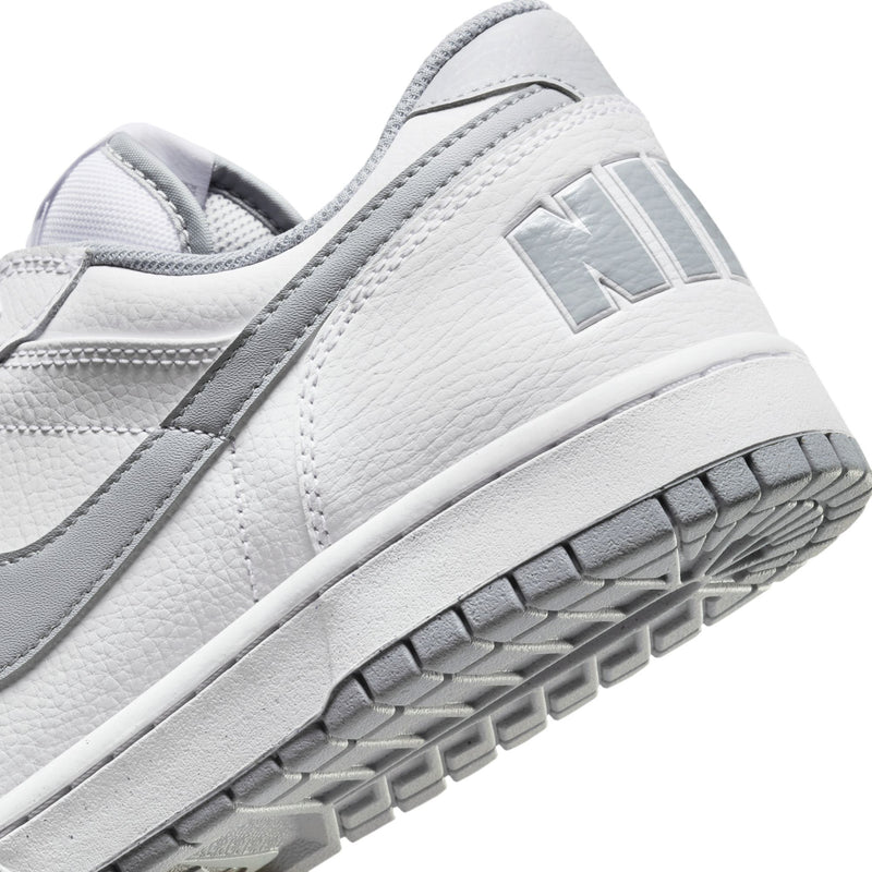 White Nike sneaker close-up with leather texture and Wolf Grey heel logo patch