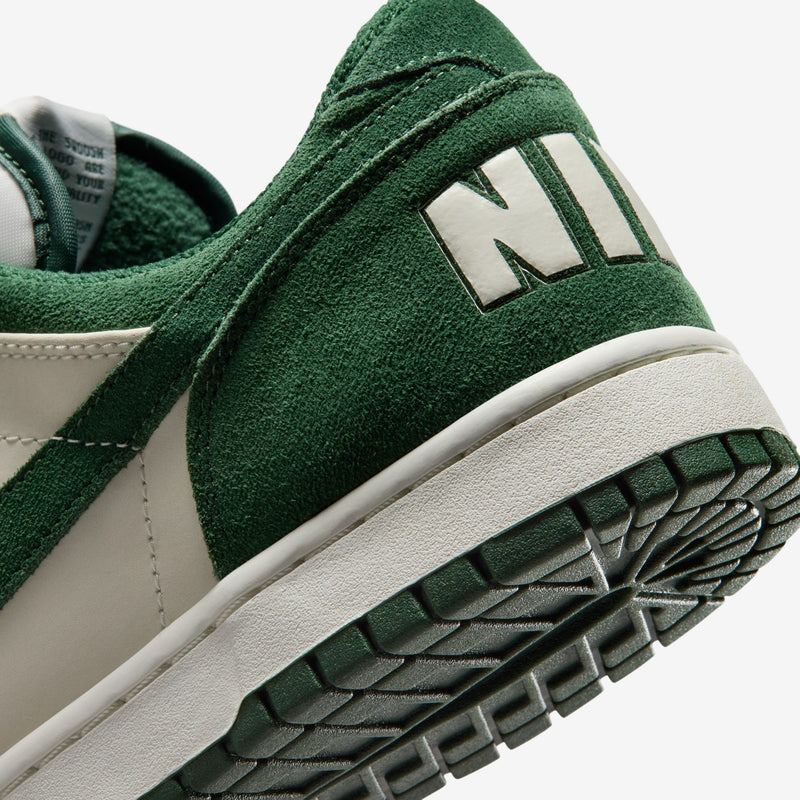 Close-up of men's Nike low-top sneakers side, dark green suede with N detail