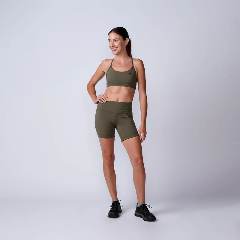 Woman in olive green GORUCK sports bra and shorts, standing in studio, fitness apparel
