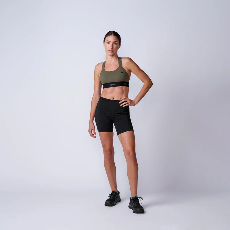 Woman wearing GORUCK olive sports bra and black shorts in studio for rucking gear showcase
