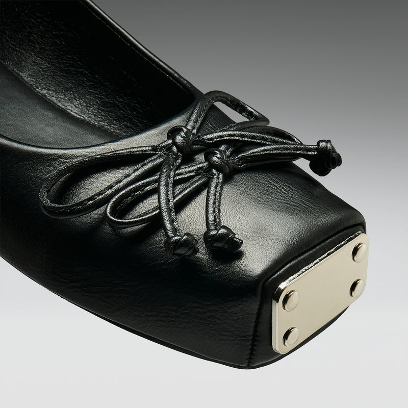 Black leather shoe with decorative laces on a gray background