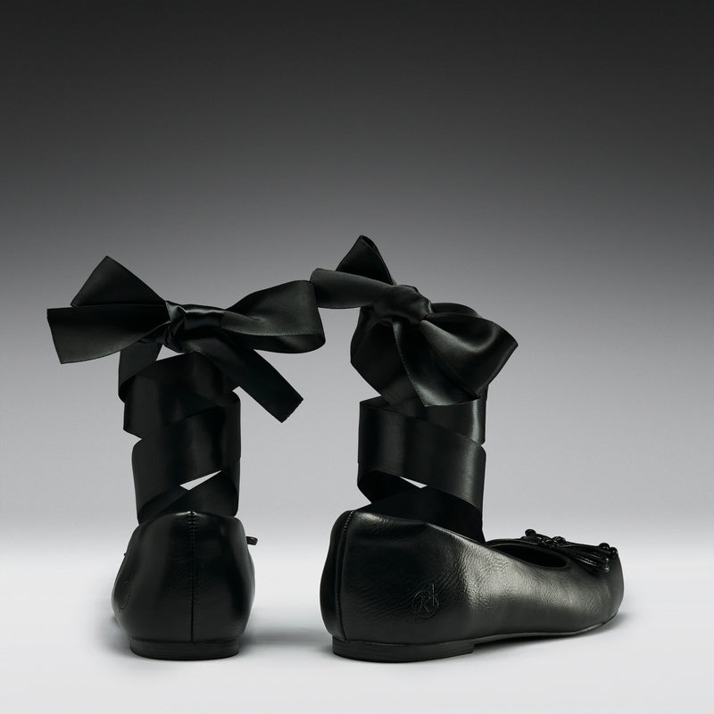 Black leather shoes with large bows on a gradient background