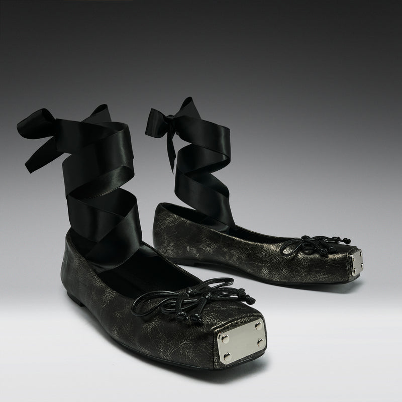 Black leather shoes with ribbons on a gray background
