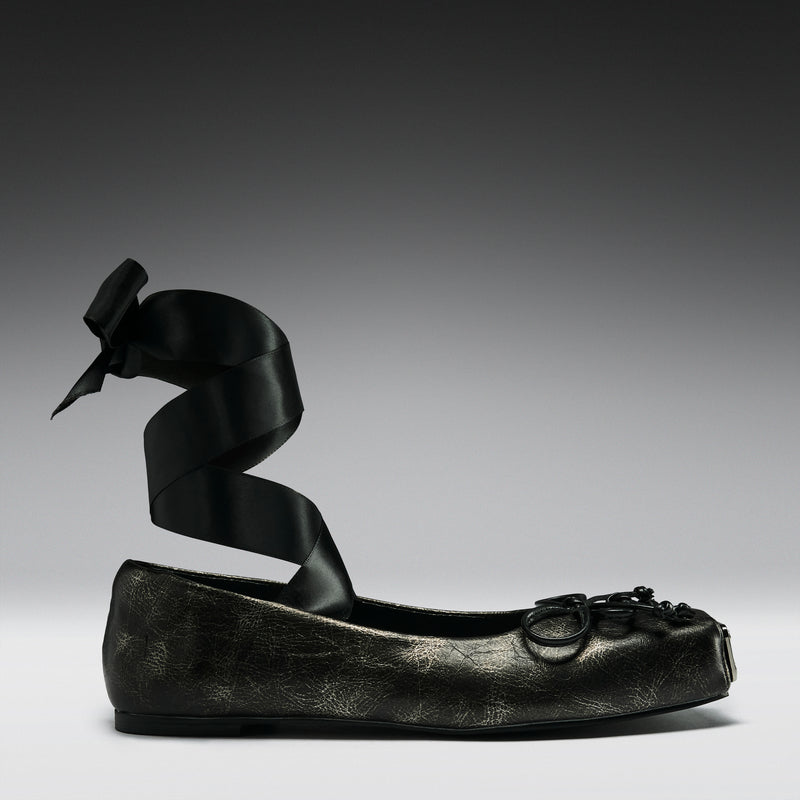 Black leather shoe with decorative bow on a gray background