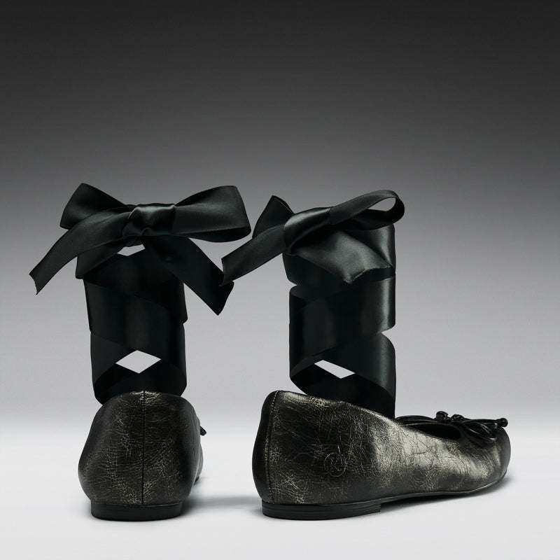 Pair of black leather shoes with ribbons on a gray background
