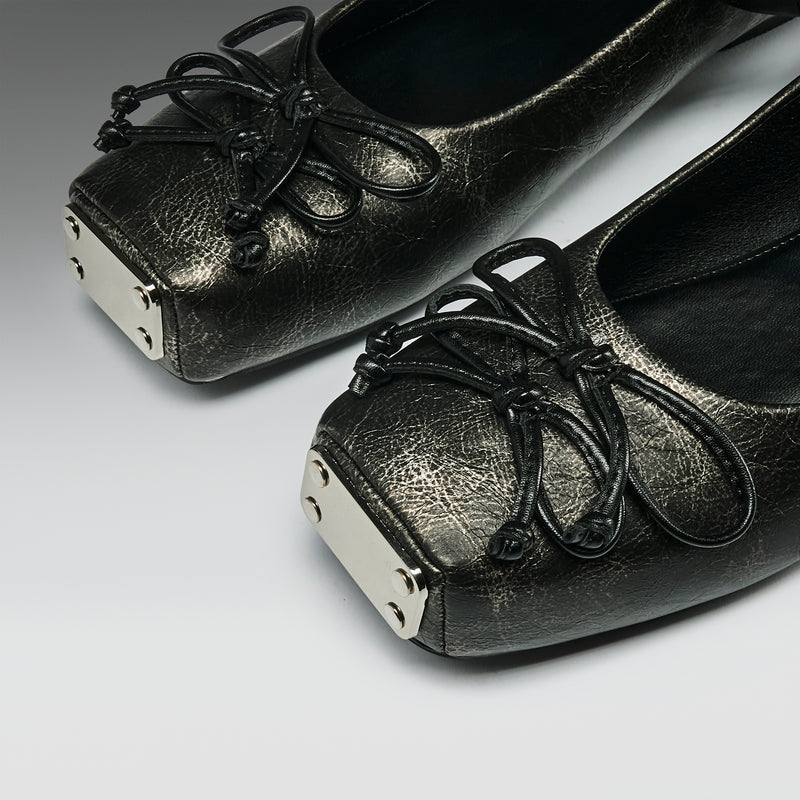 Pair of black leather shoes with decorative laces on a gray background